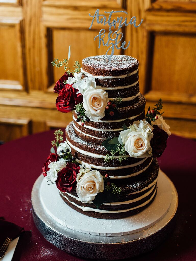 chocolate naked wedding cake decorated with white and red roses and eucalyptus