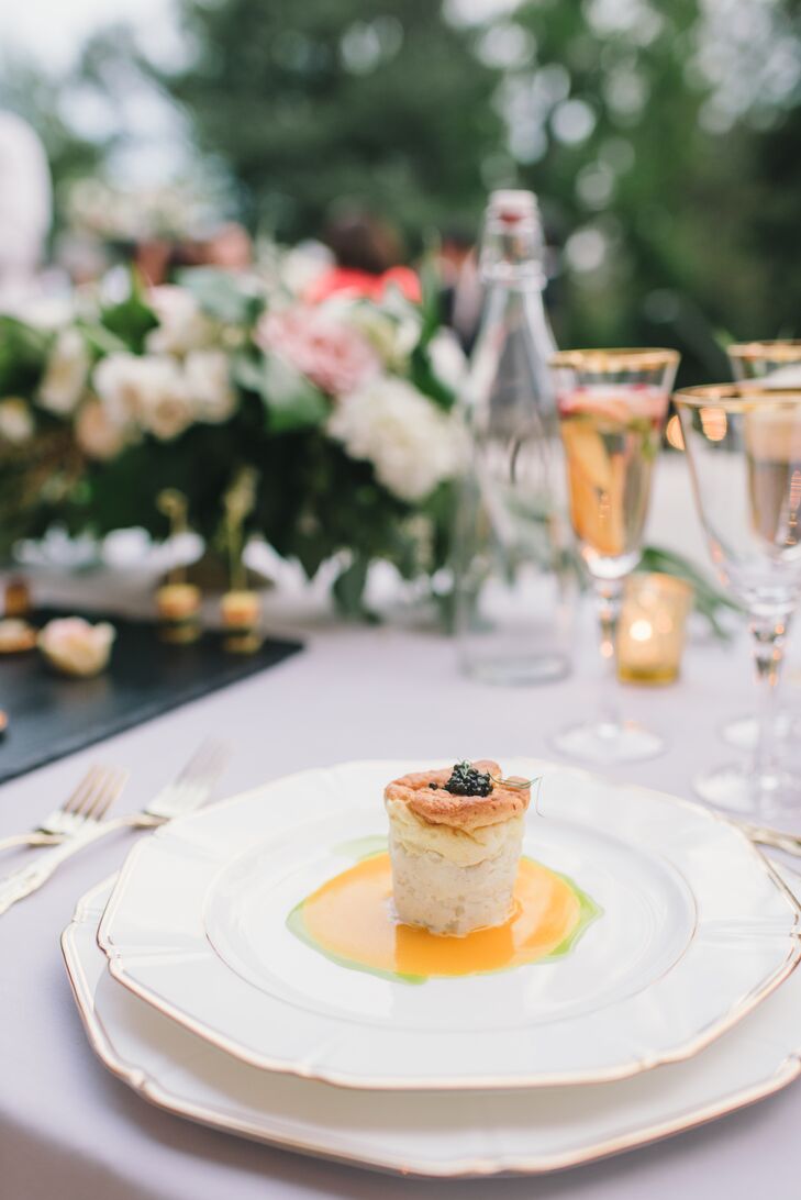 A seafood-centric menu by Le Papillon was served on light gray linen-covered tables set with gold-­accented ivory china, elegant gold flatware and gold­-rimmed glassware. Atop each place setting sat a peach napkin and a dinner menu with dusty blue font.