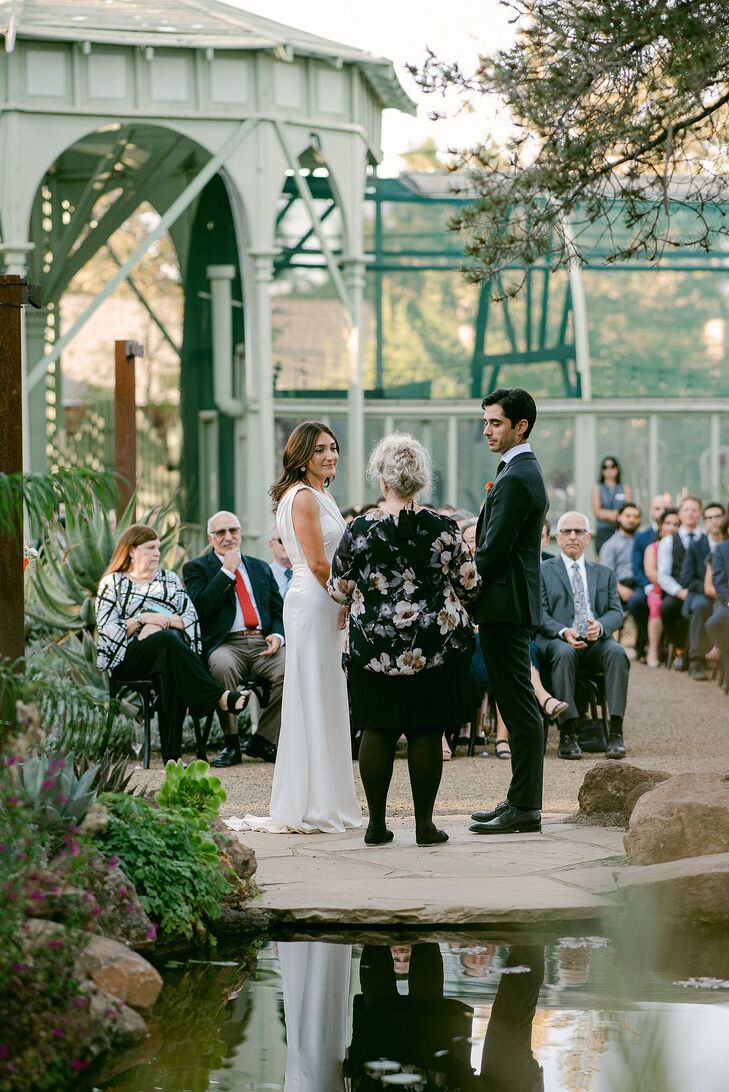 Bride and Groom At Altar With Officiant in Garden, Pond and Greenery