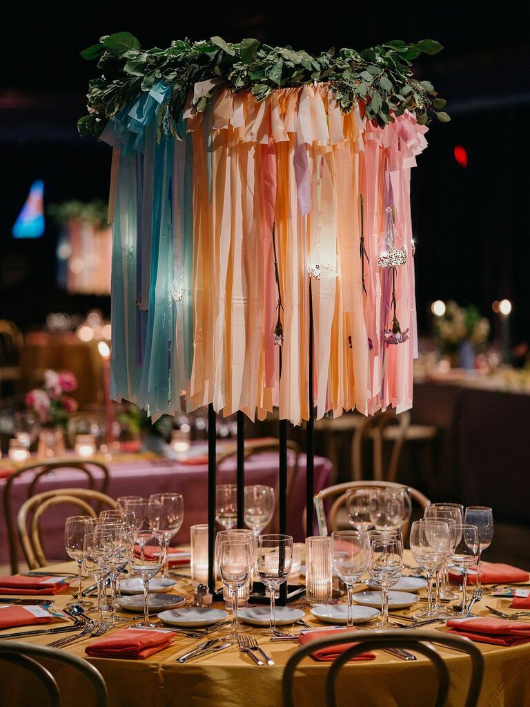 unique tall wedding centerpiece with colorful ribbons and votive candles hanging from greenery hoop