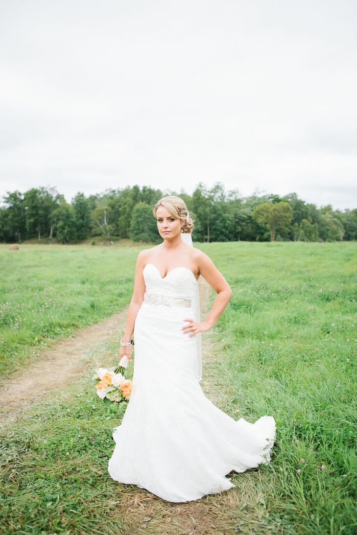 Angela wore a strapless fit and flare Allure wedding dress with lace overlay and a sweetheart neckline. She accessorized with a beaded ivory sash from a.b. Ellie and a fingertip-length veil clipped to the back of her curly updo.