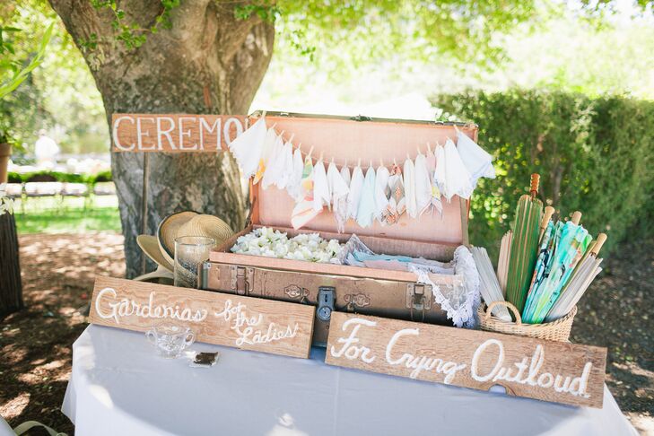 There was a table set up at the ceremony that supplied guests with everything they needed at the outdoor occasion. A leather vintage trunk was opened and displayed a line of hanging handkerchiefs, and the trunk was half-filled with gardenia flowers to throw during the recessional while the other half was filled with more handkerchiefs. Hats and parasols were available for guests to use during the sunny summer day.