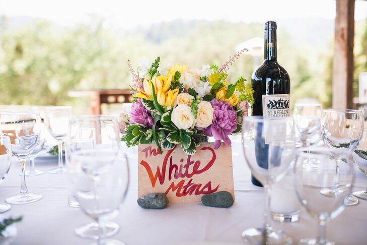 The reception took place inside the rustic barn at Rancho Otranto in Helena, California. Dining tables were marked with names of locations painted onto planks of wood, propped up by small rocks. Centerpieces were filled with pastel flowers of hydrangeas, lilies and roses with accents of greenery.