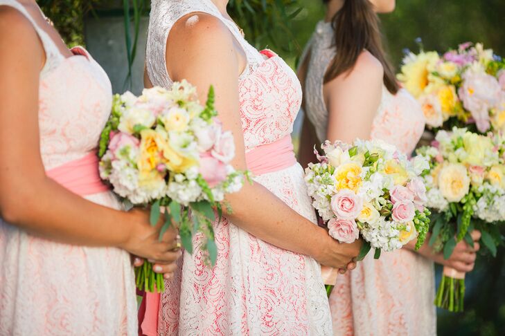 The bridesmaids wore white lace wedding dresses lined with various shades of pink, and they wore a sash in a matching color that was wrapped around the waist. Their pastel bouquets were filled with hydrangeas, roses, lilies and peonies accented with veronica .