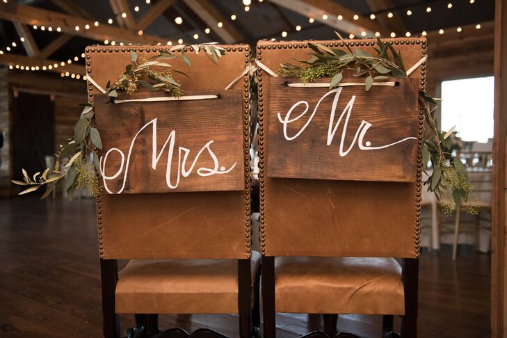 Green vines and hand-painted rustic wooden signs adorned the backs of the bride's and groom’s chairs at the reception. The warm brown leather was the perfect touch under the exposed wooden beams and worn wooden floors of the venue.