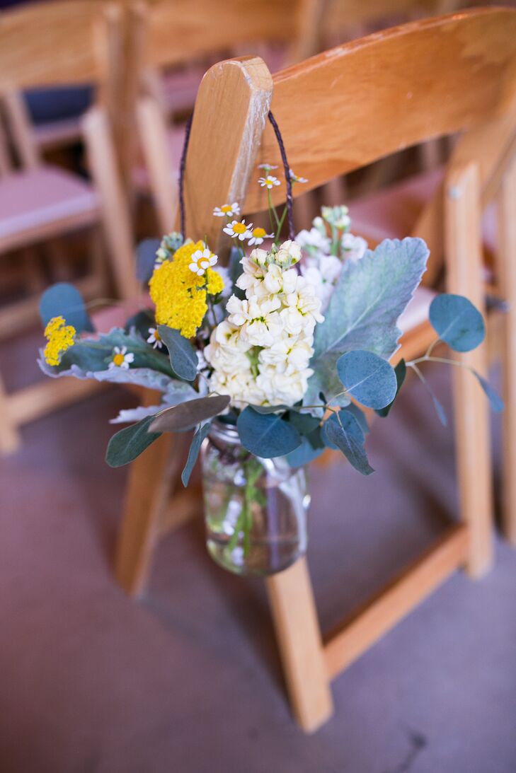 Lauren walked down the aisle lined with hanging glass vases, filled with white and yellow flowers. She and her bridesmaids matched the decorations with their bouquets incorporating similar colors and blooms.
