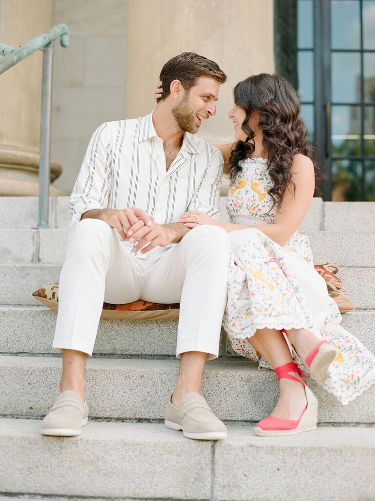 Couple sit on steps during their engagement photo shoot. 