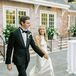 Groom in Classic Tuxedo, Calla Lily Boutonniere and Bride in High-Neck, Silk Gown Walking into Reception