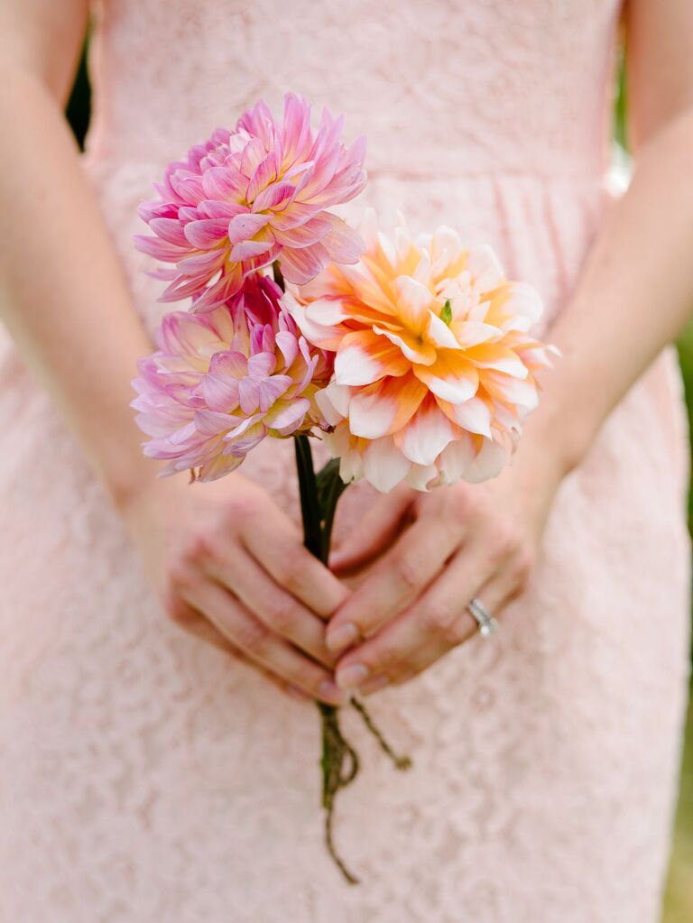 A bride holds this springtime bouquet of peach and pink flowers.