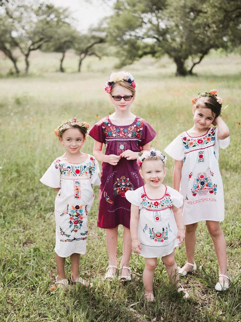 Four flower girls wearing colorful traditional embroidered Mexican dresses.