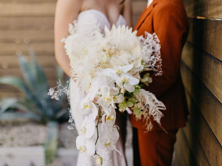 unique fall wedding bouquet with orchids, dried fan palms and pampas grass
