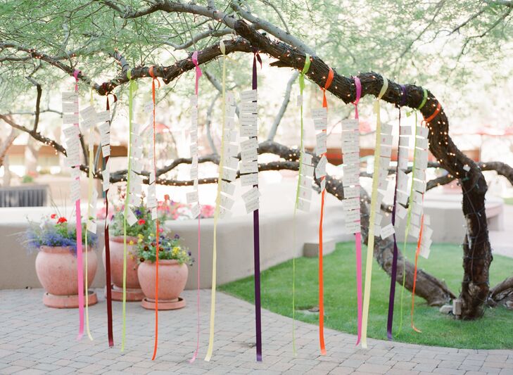 Escort cards hung from jewel-tone-hued ribbons that dangled from a tree branch.