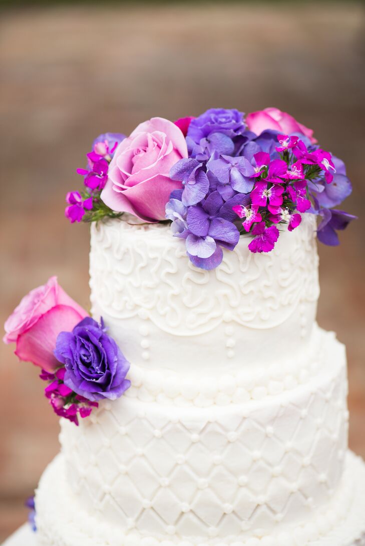 The traditional white round cake was topped with an array of purple and pink florals and piped in alternating cushion patterns and damask patterns.