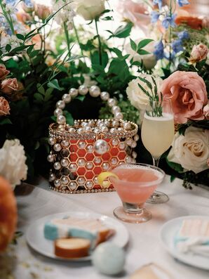 Unique, Transluscent Pearl Purse on Dining Table With Different Cocktails, Verdant Flowers