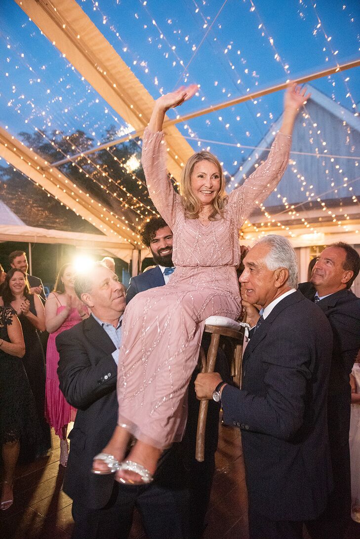 Woman in a Pink Dress Lifted in a Chair During Hora at Jewish Wedding