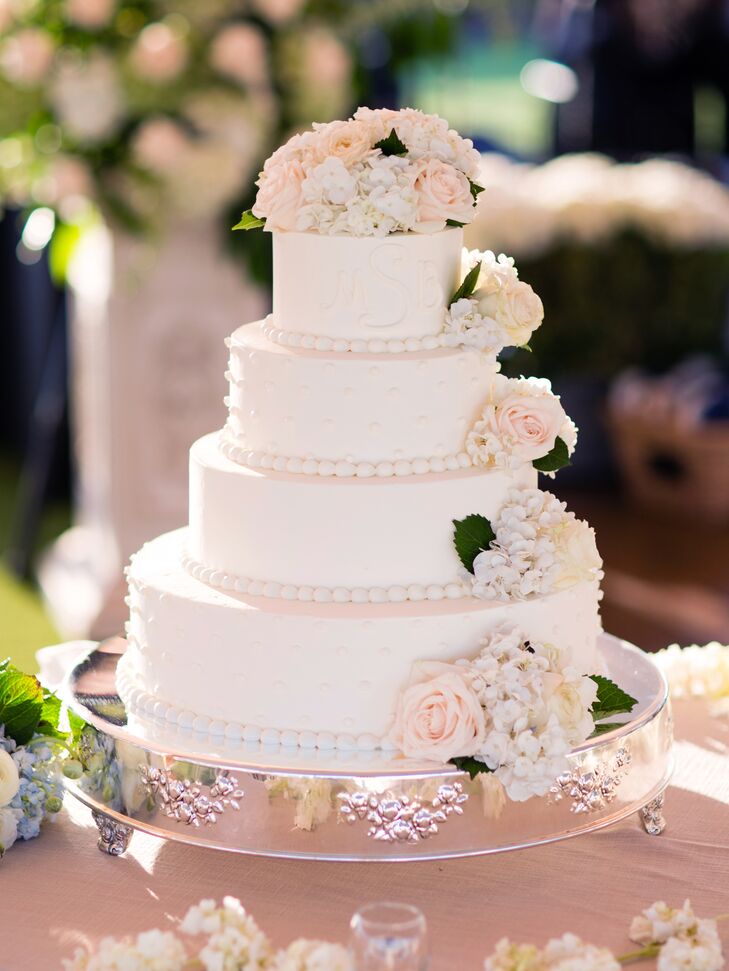 The four-tier white cake had fresh flowers on the top layer and cascading down the sides.