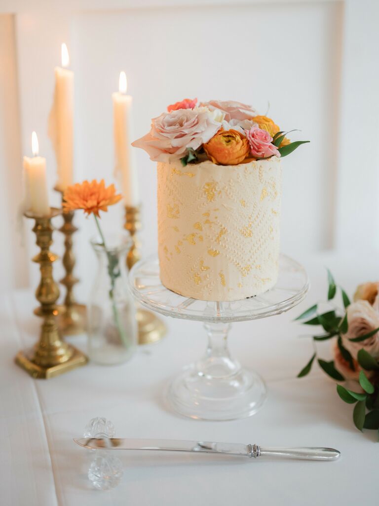 small one tier wedding cake with gold leaf, textured fondant and pink and orange flowers