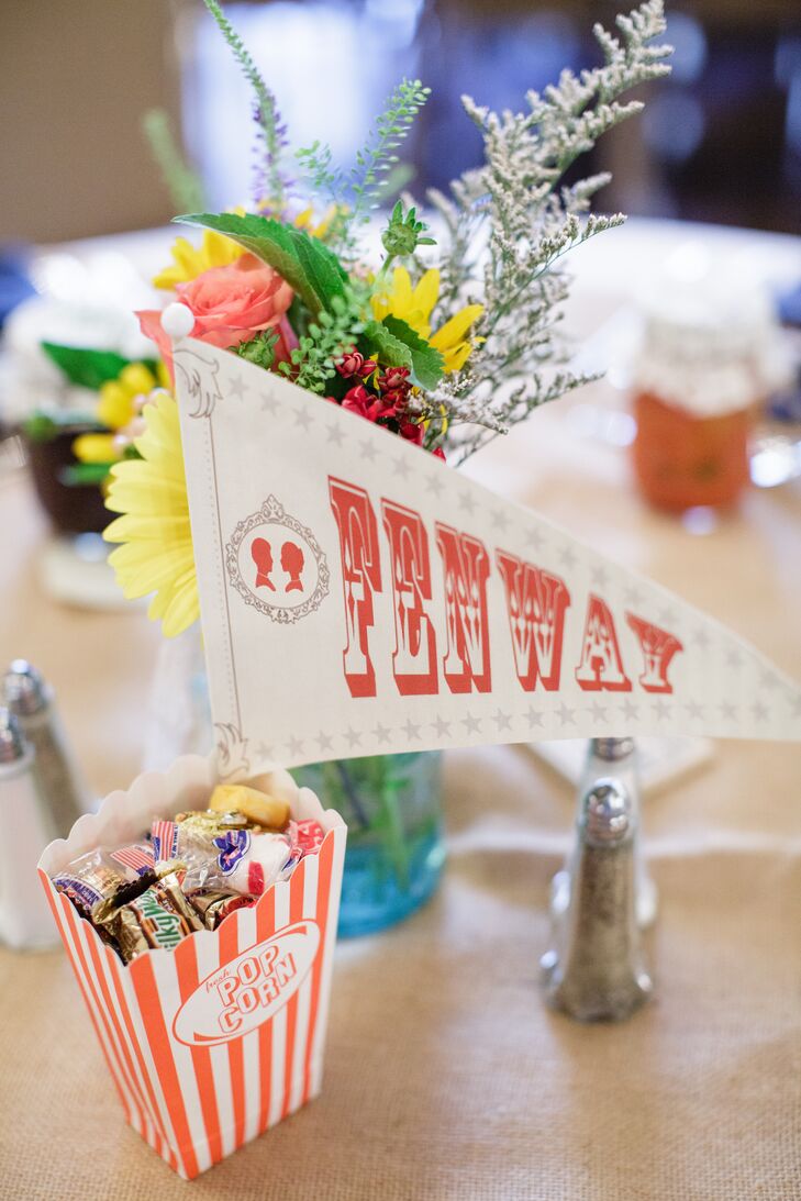 Vintage-inspired country fair pennant flags paired with mason jars filled with wildflowers served as the centerpiece on each dining table. Each table was named after a significant place or event in Marisa and Evan's life together, such as the college where they fell in love, their first apartment together and their honeymoon destination.