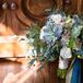 “Annie chose bouquets that were more wild, natural, and textured rather than tightly formed,” the couple says. “Bouquets made of cafe au lait dahlias, spray roses, succulents, blue eryngium, white freesias, seeded lemon leaves, mums and seeded eucalyptus sprayed gold were wrapped with gold and dark teal ribbons to match the palette.”