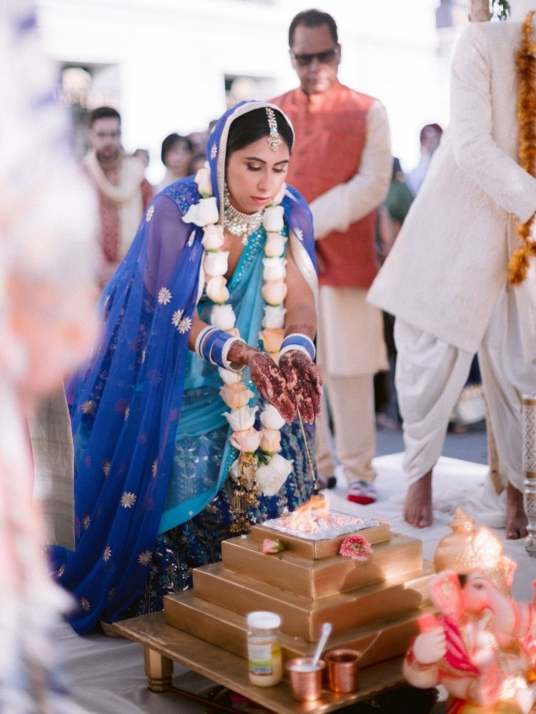 bride tossing rice into holy fire during Hindu wedding ceremony