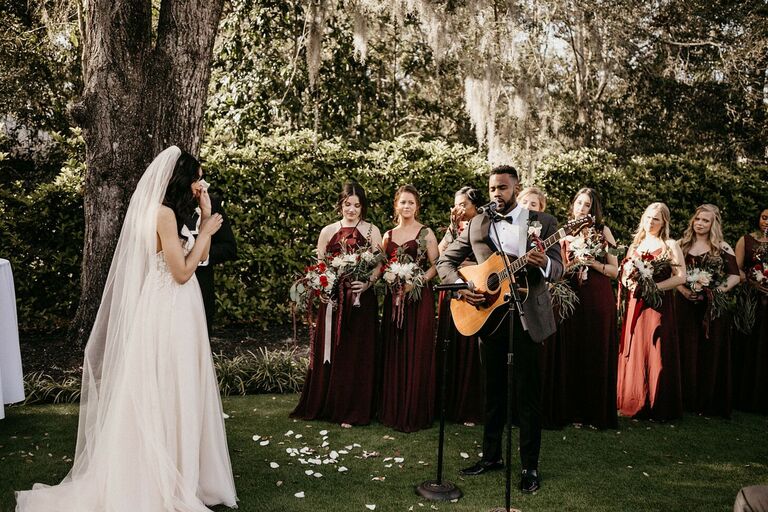 Groom playing guitar and singing song during ceremony