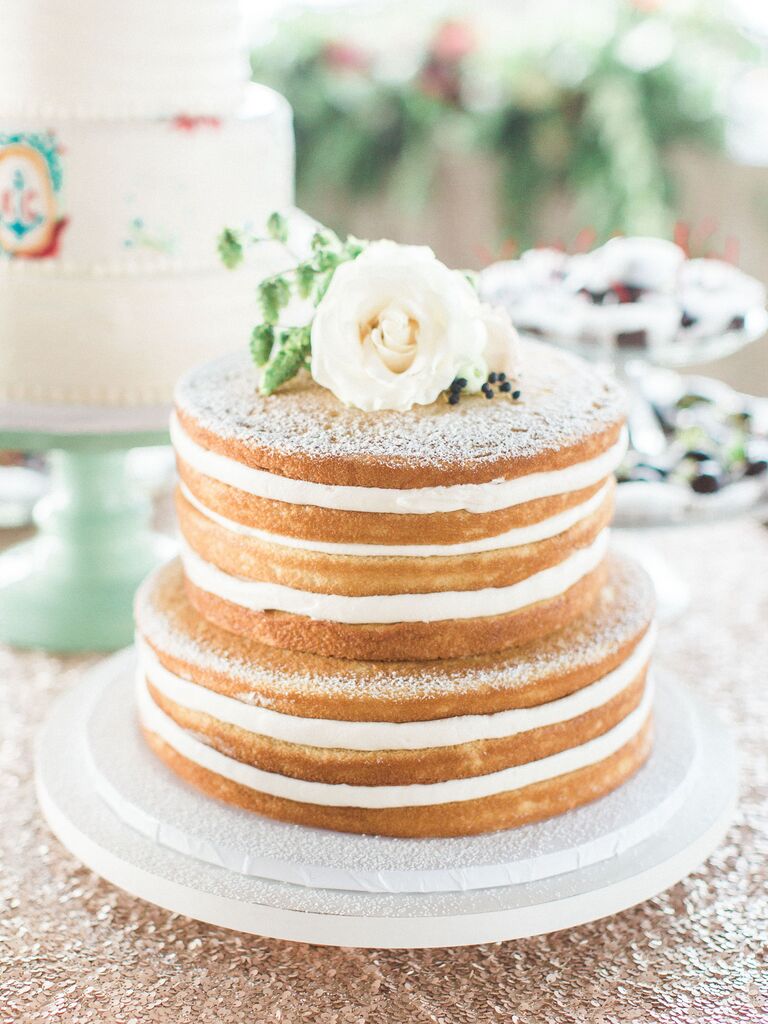 simple two tier naked wedding cake decorated with powdered sugar and white flower