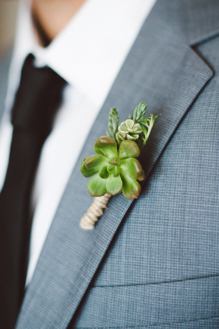 Chris wore a boutonniere made up of a large green succulent surrounded by smaller succulents that were tied together and pinned to his light gray lapel on his suit. He wore a white collared shirt under his jacket with a simple black tie.