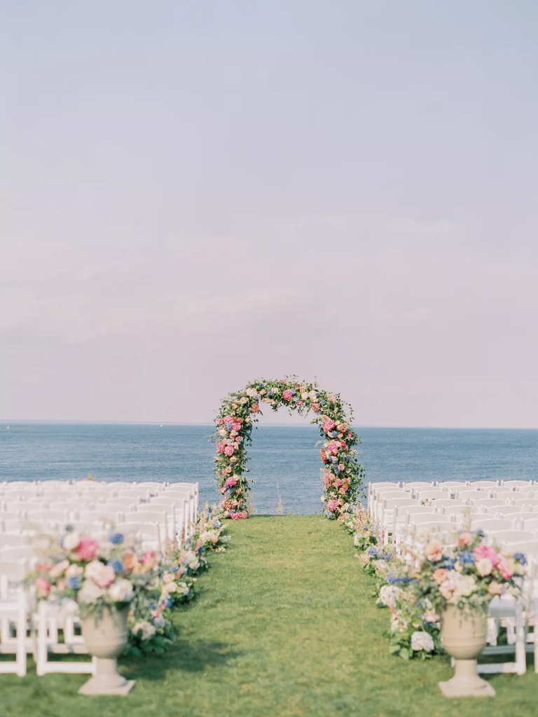 A vibrant pink floral arch welcomes guests to their seats.