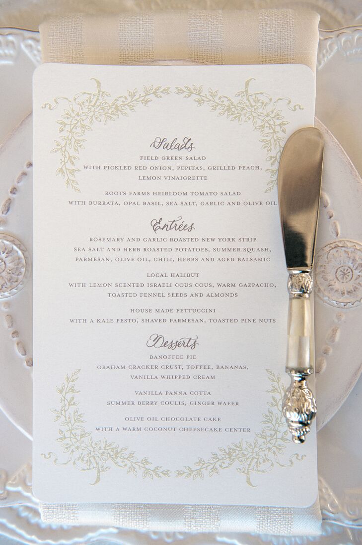 White stationery with gold designs bordering around the text let guests know of what to expect for the upcoming meal. White plates set under the menus added to the overall elegant setting.