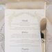 White stationery with gold designs bordering around the text let guests know of what to expect for the upcoming meal. White plates set under the menus added to the overall elegant setting.
