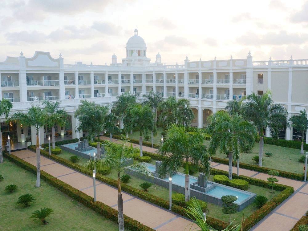 Aerial view of a white hotel with palm trees