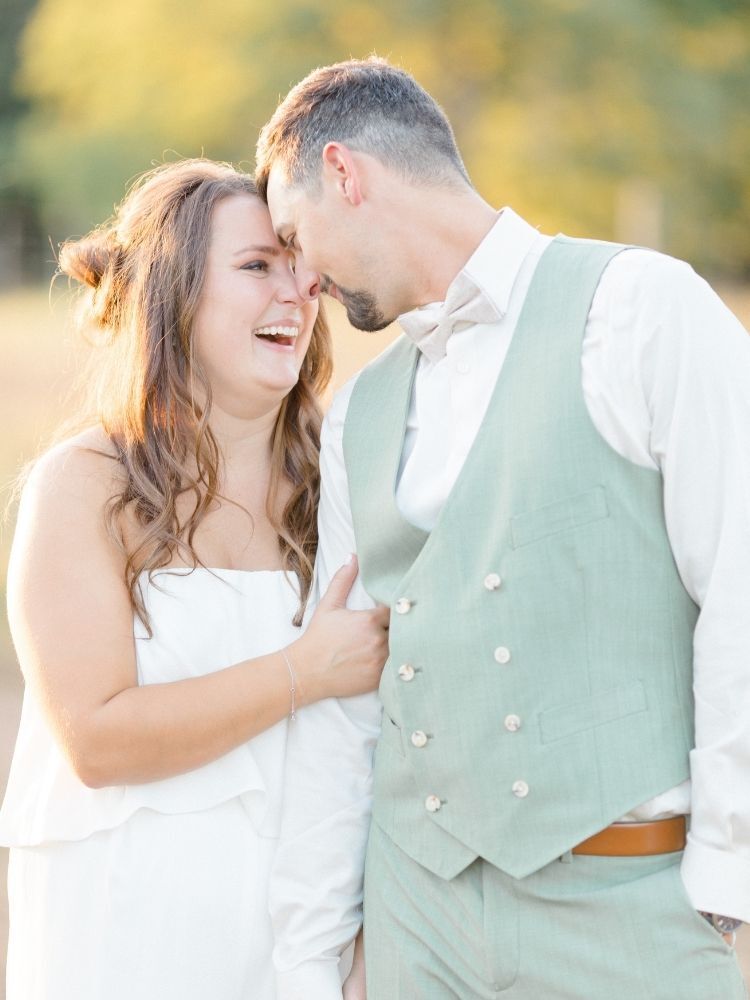 couple smiling and hugging during sunset engagement photo shoot