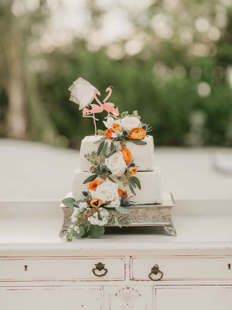 Three-tier square beach wedding cake with oranges and flamingo topper