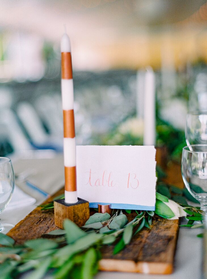 While the couple opted against farm tables, they used lengths of foraged wood to achieve a similar effect. The wooden panels gave way to flickering table candles wrapped in copper-striped taper candles and bundles of fresh greenery for a beautifully bohemian look.