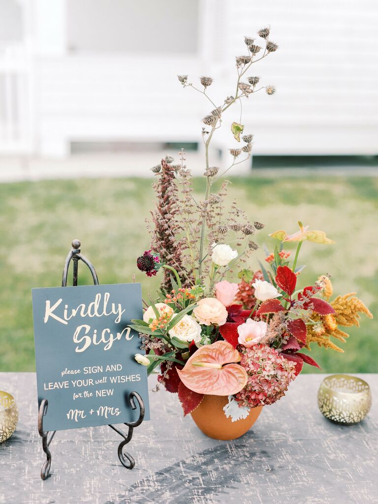 handwritten welcome sign next to modern fall wedding flower arrangement