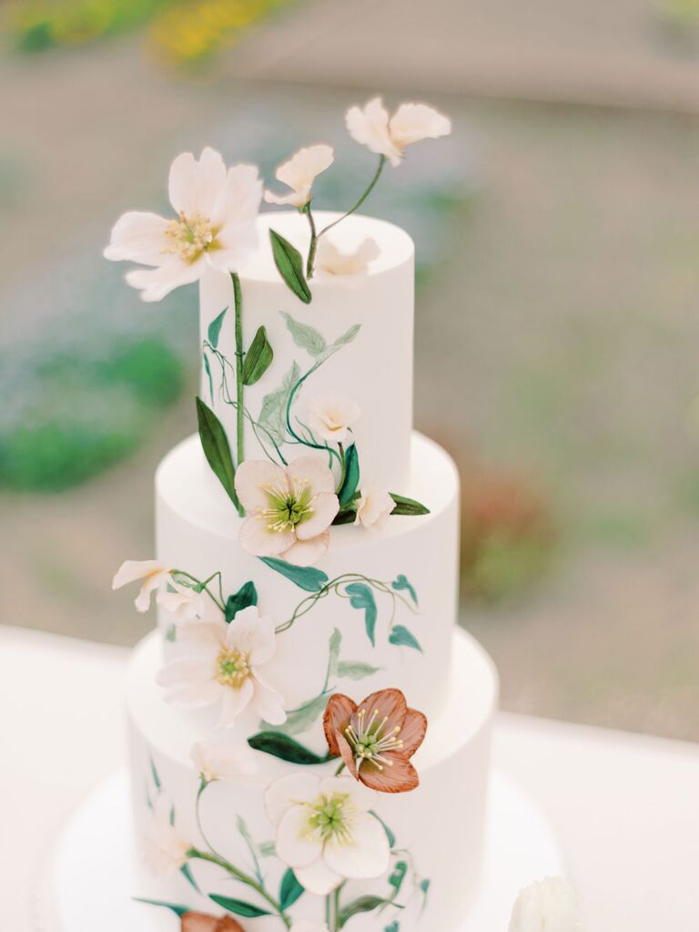 Three-tier white bridal shower cake with hand-painted floral greenery