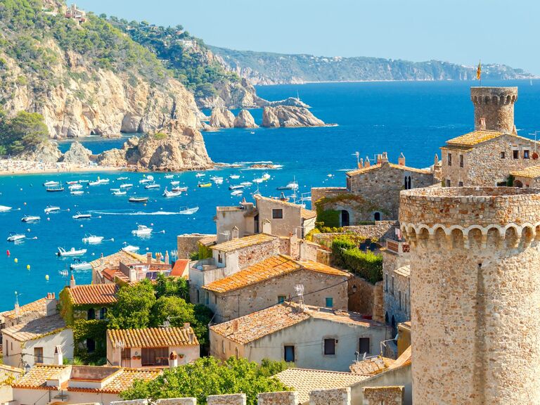 View of the Costa Brava coastline that features beautiful historic buildings and a sparkling ocean. 