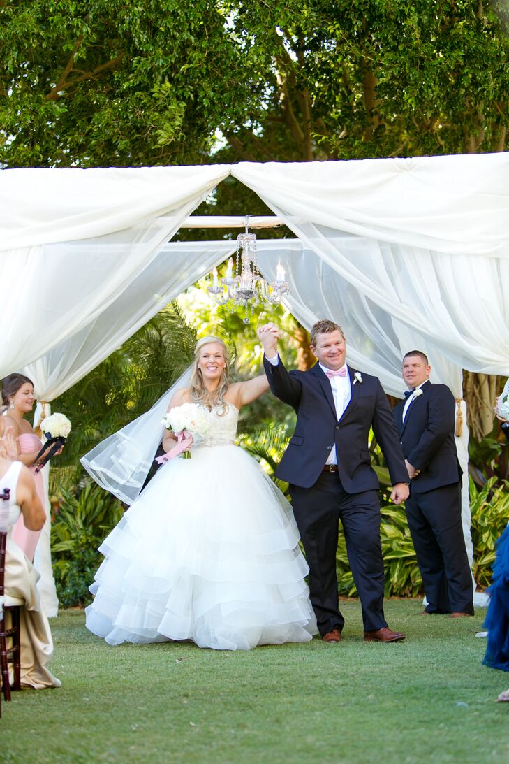 After a trip to Men's Wearhouse, Andy and his groomsmen were ready for the celebration with dapper navy tuxedos by Tommy Hilfiger. Andy, however, still stood out from the pack. He started the recessional with Lauren in a distinct look that included a pink bow tie and white ranunculus boutonniere.