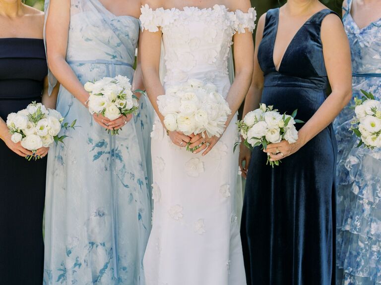 Bridesmaids wear alternating light blue floral gowns and solid colored navy gowns. 