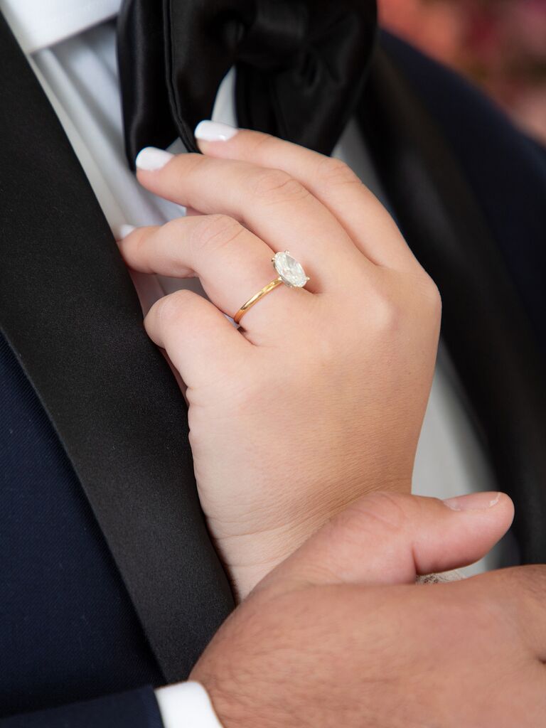 Bride wearing oval-cut engagement ring on yellow gold band