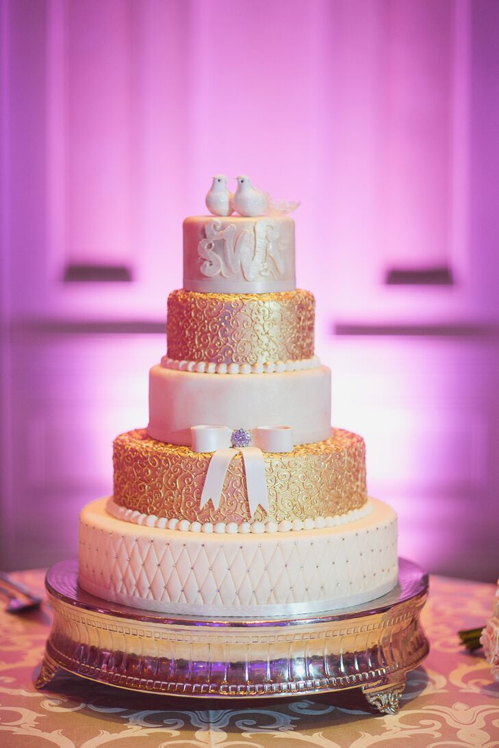 Shayna and Nick enjoyed a five-tiered fondant cake altering between ivory and gold with the top tier displaying the couple’s monogram and topped with two white lovebirds.