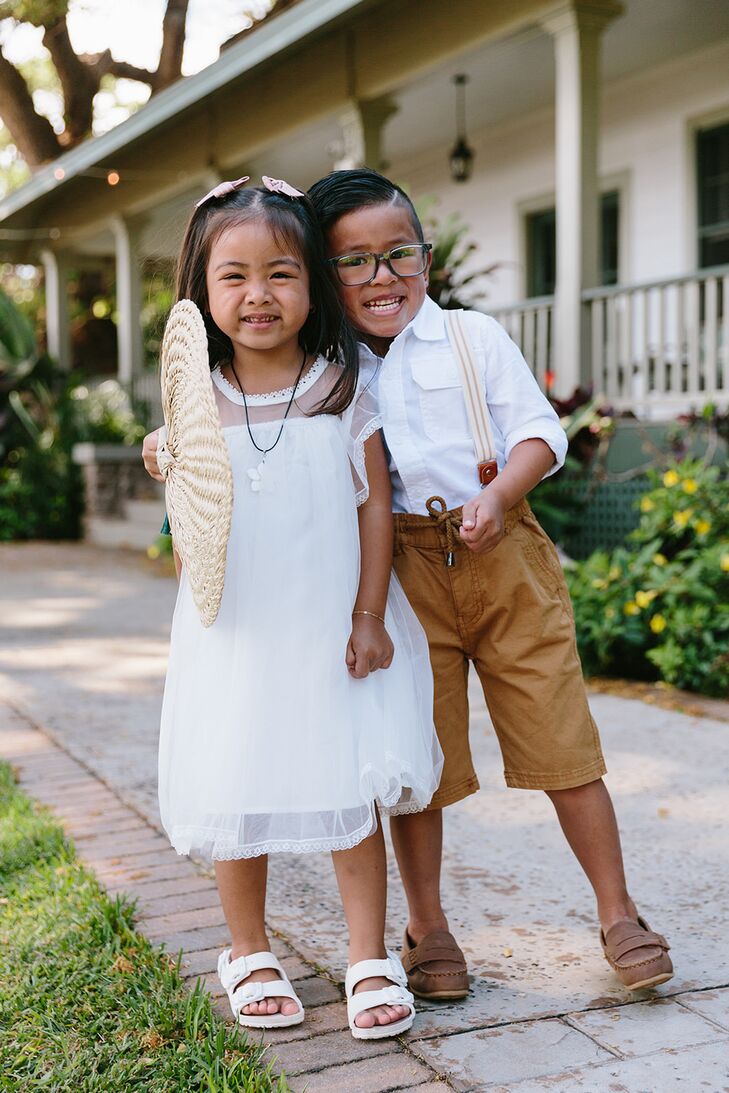 Two Young Kids in Formalwear With a Fan Smiling at Outdoor Wedding in Hawaii