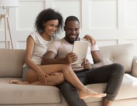 Couple sitting on the couch and looking at a tablet