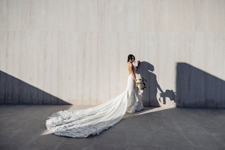 Bride With Long Train Poses Against Wall