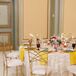 Round Dining Tables With White-and-Gold Linens, Yellow Napkins, Low Centerpieces