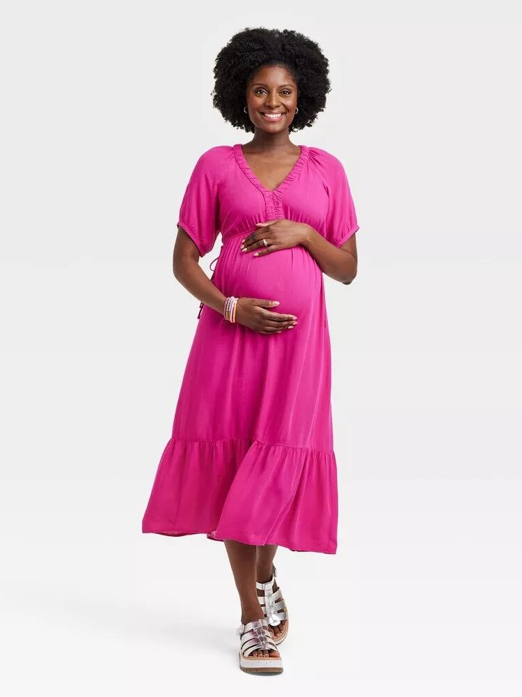 Model wears a pink dress with a ruffled hem. 