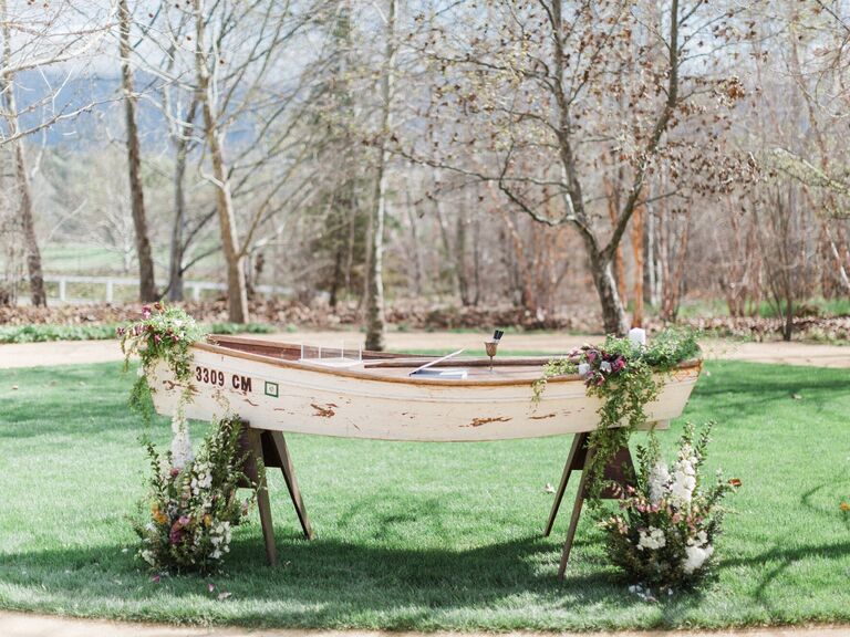 wooden rowboat decorated with flowers and greenery repurposed into wedding gift table 