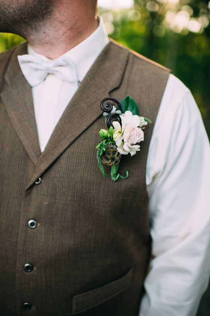 Kim and her bridesmaids weren’t the only ones with chic, garden-style accents. Nick stepped into the ceremony with a natural arrangement upon his neutral vest. Designed by Ibranyi Is Floral, its green wrap contained silver brunias, bold fiddlehead ferns, white veronica and scabiosa. A white carnation marked the center alongside leaves for texture.