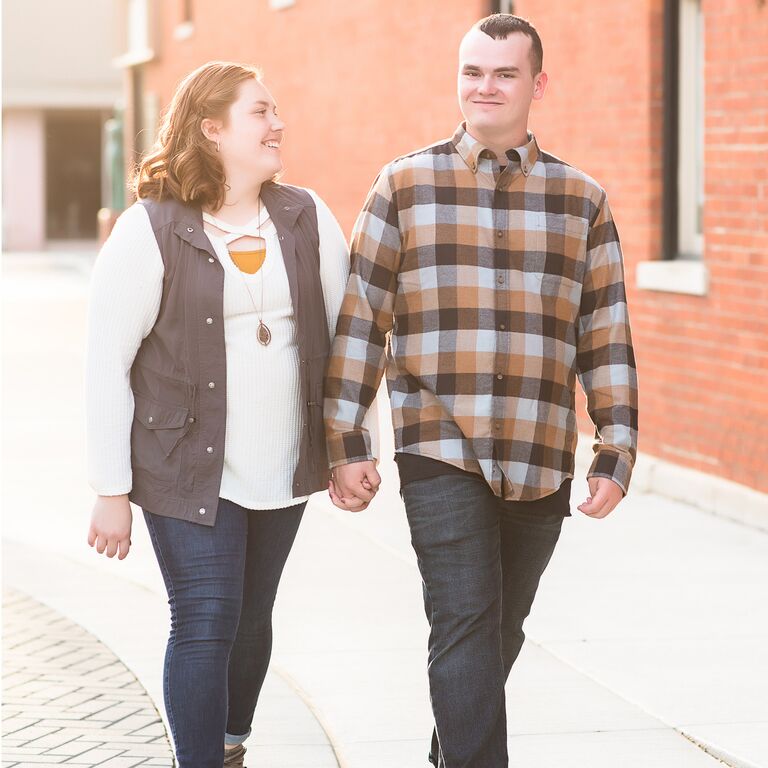 Couple wearing fall outfits holding hands while walking
