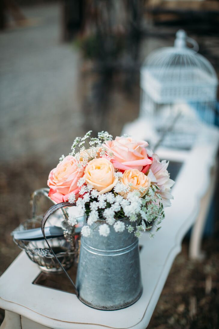 Peach and coral roses mixed with Queen Anne's lace filled a tin pitcher, which added to the overall shabby-chic vibe. Many similar flower arrangements filled with soft-colored blooms made an appearance at the wedding as well.